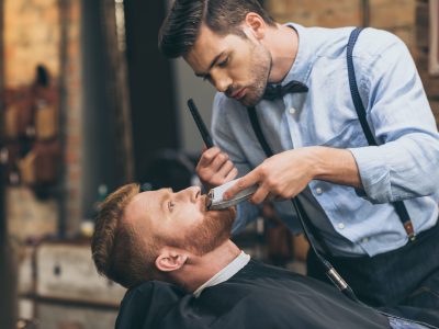 male-barber-trimming-customers-beard-in-barber-shop.jpg